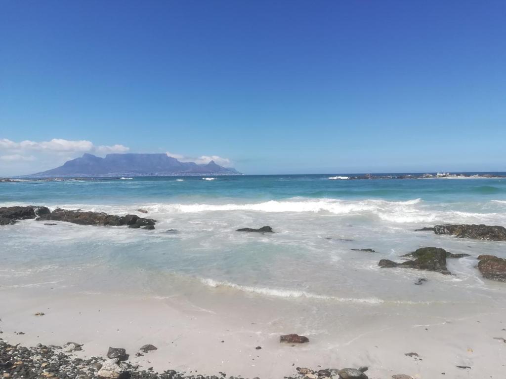 a beach with rocks and the ocean with a mountain in the background at 404 Horizon Bay in Bloubergstrand