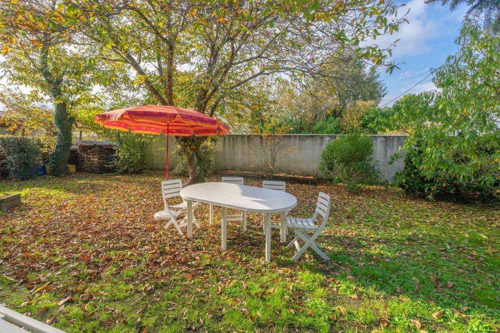 - une table et des chaises avec un parasol dans la cour dans l'établissement Vacances proche de la Palmyre, à Étaules