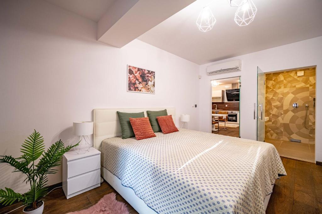 コシツェにあるAR CASALUX apartmentの白いベッドルーム(オレンジ色の枕が付くベッド付)