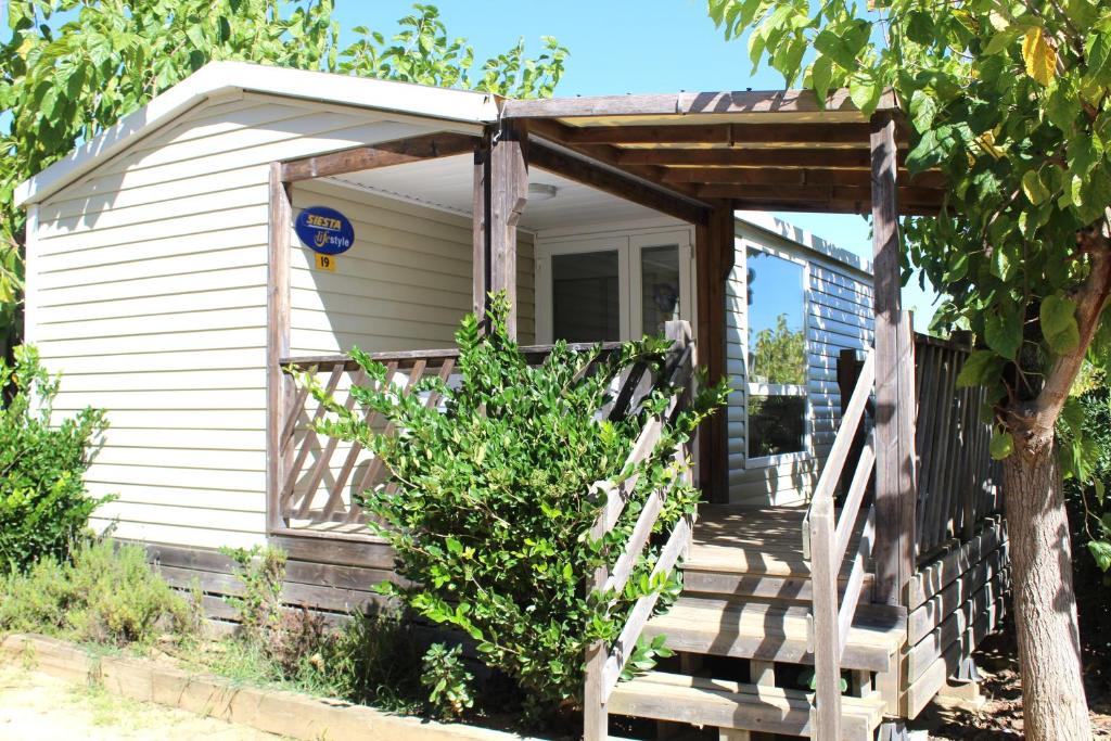 a small white house with a wooden porch at Camping Tucan - Mobile Homes by Lifestyle Holidays in Lloret de Mar