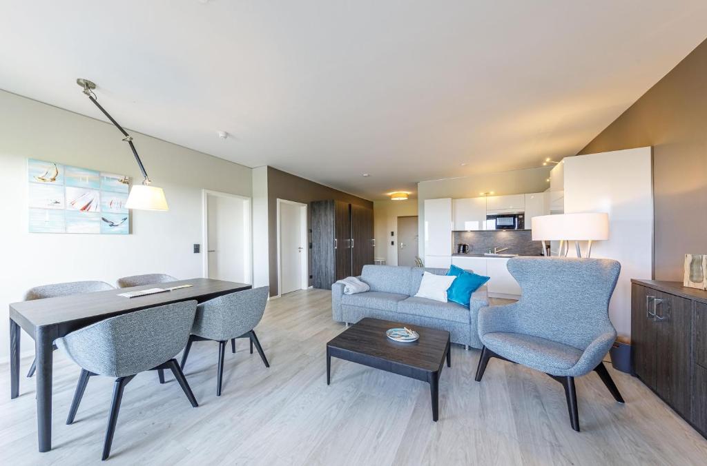 a living room with a couch and a table and chairs at Dünenquartier - 3 Obergeschoss mit Ostseeblick - 600m zum Strand in Wustrow