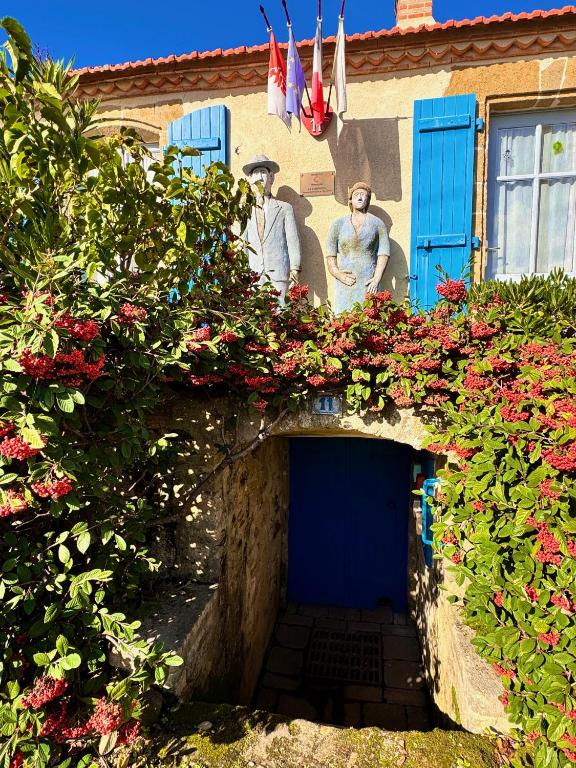 un bâtiment avec une porte bleue et quelques fleurs dans l'établissement Demeure François de l'Isle du Fief - Charme unique, à La Barre-de-Monts