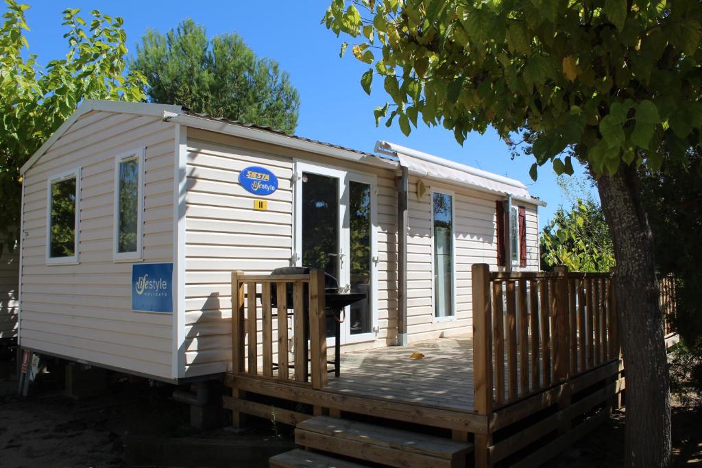 a white tiny house sitting on a wooden deck at Camping Tucan - Mobile Homes by Lifestyle Holidays in Lloret de Mar