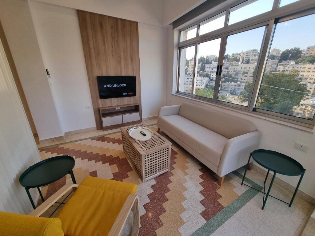 a living room with a couch and a tv at Downtown Living Boutique Apartments in Amman