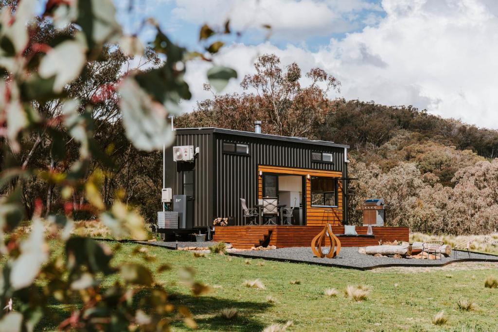a black tiny house sitting on top of a field at Wildnest Wilderness in Turondale