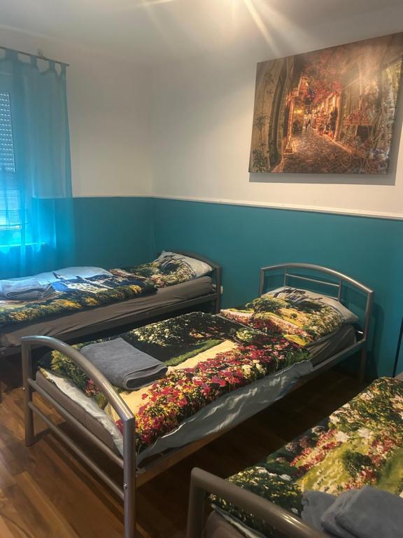 three beds in a room with a painting on the wall at Pension Sonnenschein in Betzdorf