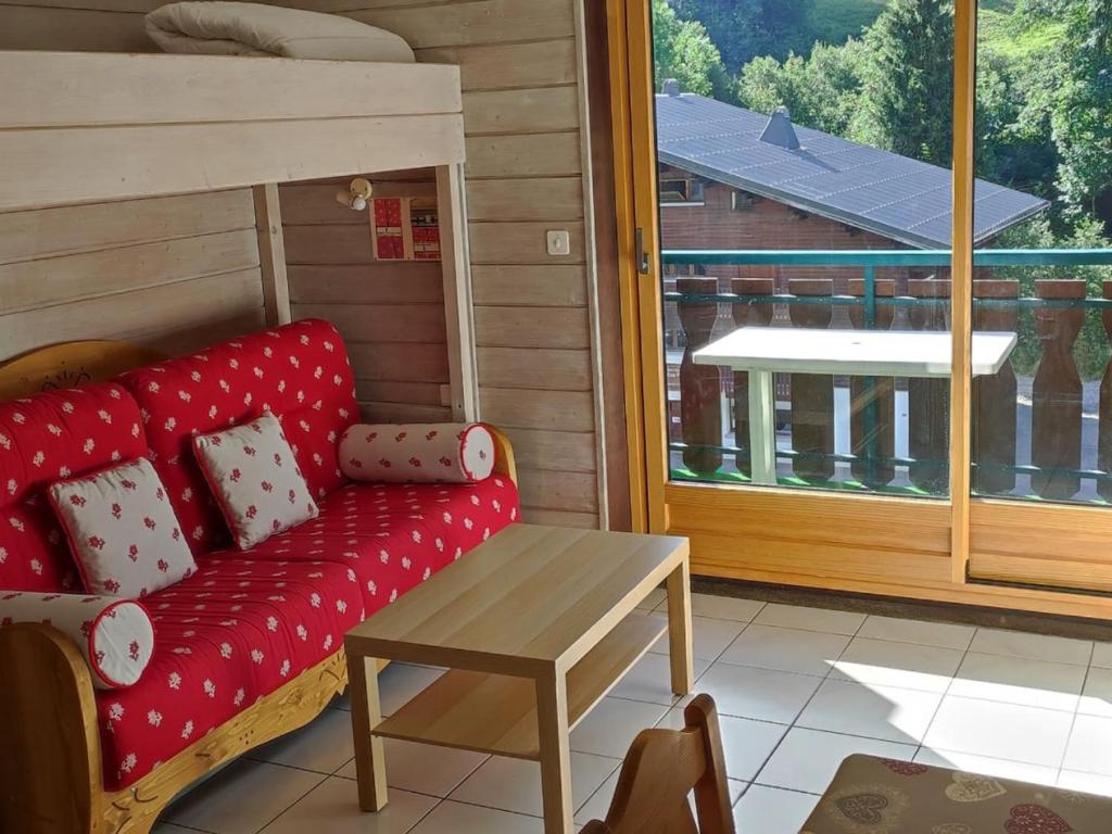 - un canapé rouge assis sur une terrasse couverte avec une table dans l'établissement Studio avec Balcon Sud, à 100m des Remontées Mécaniques, Parking Gratuit, Pour 4 Personnes - FR-1-676-98, à Châtel