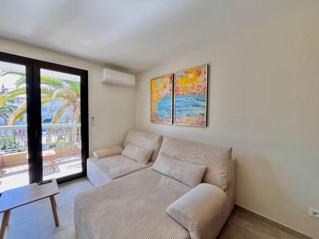 un salon avec un canapé et une fenêtre dans l'établissement LE TRAVOLTA avec merveilleuse terrasse, chic et lumineux à deux pas du centre-ville, à Cannes