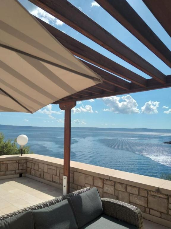a view of the ocean from a patio with an umbrella at Apartments and Rooms Ref in Sumartin