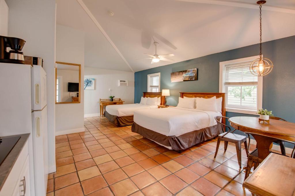 Cet appartement comprend une chambre avec deux lits, une table et une cuisine. dans l'établissement Pelican Suite - Southernmost Sanctuary, à Key West