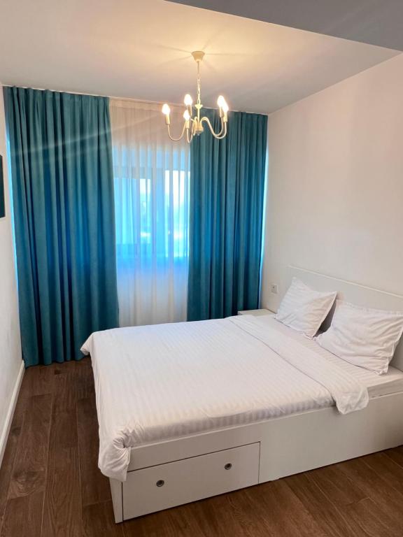 a bedroom with a bed with blue curtains and a chandelier at Central Metropolitan Bright 1 in Iaşi