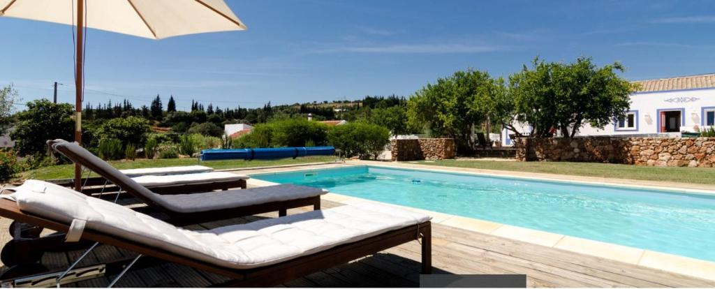 a swimming pool with two lounge chairs and an umbrella at Casa da Nora in Silves
