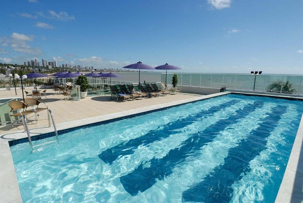 a large blue swimming pool with chairs and umbrellas at Blue Sunset Suites in Penha