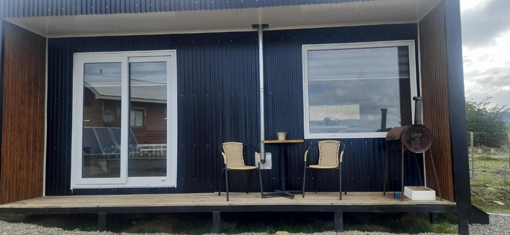 ein kleines Haus mit drei Stühlen auf einer Terrasse in der Unterkunft Cabañas Campestres Altos de Leñadura Punta Arenas in Punta Arenas