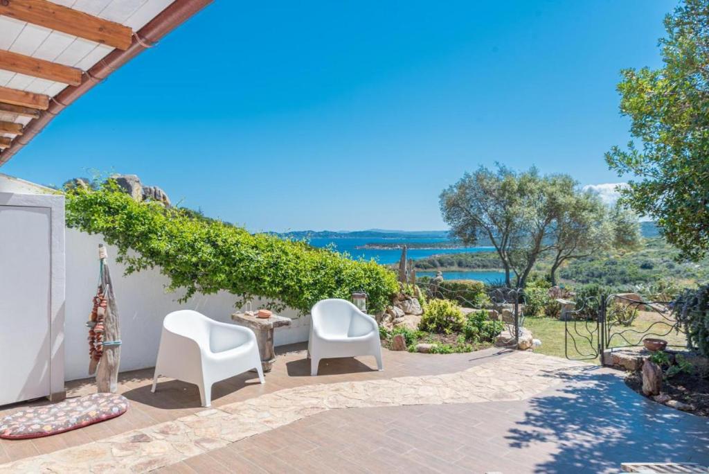 een patio met 2 witte stoelen en een tafel bij Villa Asfodelo a Valle Dell' Erica in Valle Dell’Erica