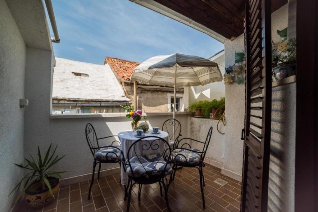 a table and chairs on a balcony with an umbrella at Apartments Ela in Sutivan