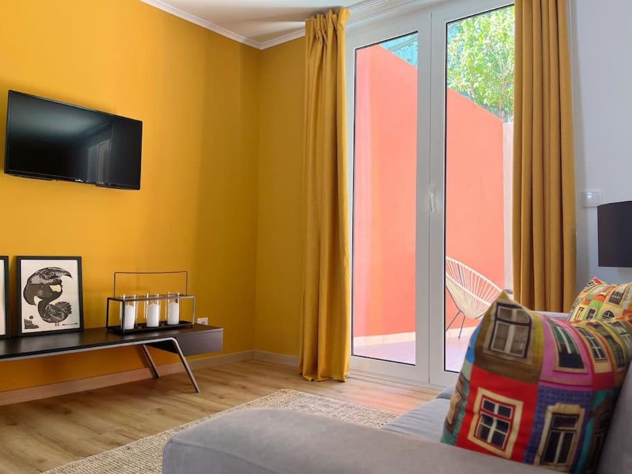 Una sala de estar con un sofá y una puerta corrediza de vidrio. en Casa Nêspera, en Lisboa