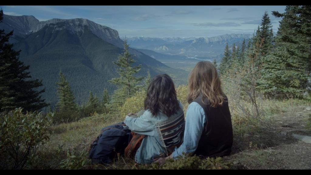 two women sitting on a hill looking at the mountains at Jasper East Hostel - Near Jasper National Park East Gate Entrance in Jasper
