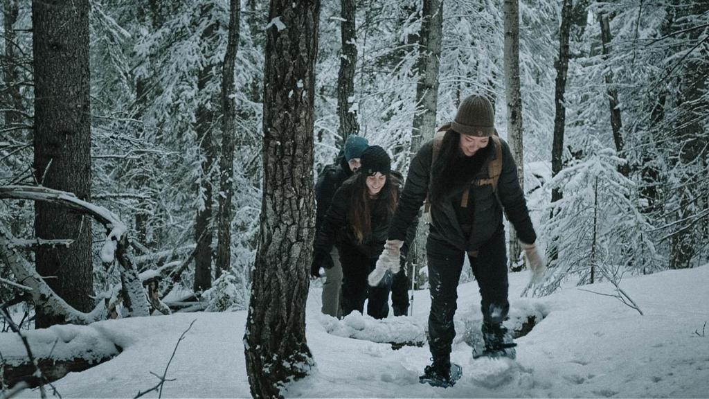 a group of people walking through a snow covered forest at Jasper East Hostel - Near Jasper National Park East Gate Entrance in Jasper