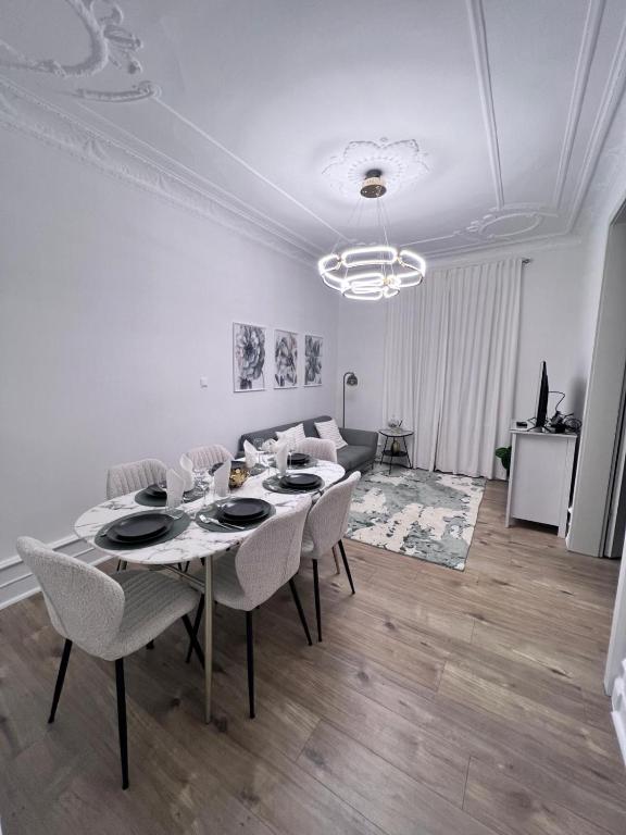 une salle à manger blanche avec une table et des chaises dans l'établissement Le Rapp 6, Appartement de Standing 3 chambres, 7 personnes &1 bébé, Cosy et familial ultra équipé Emplacement Idéal proche Gare Centre ville Marchés de Noël Quartier Tribunal Contades, à Strasbourg