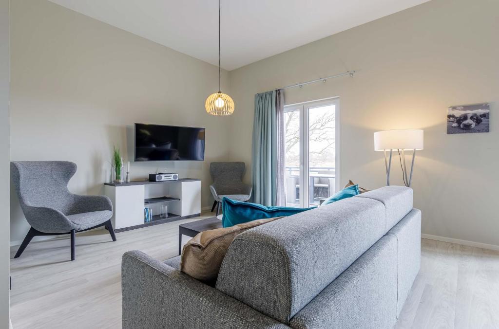 a living room with a gray couch and a tv at Boddentraum - 5 Sterne Ferienwohnung mit Blick auf das malerische Ostseebad Wustrow in Wustrow