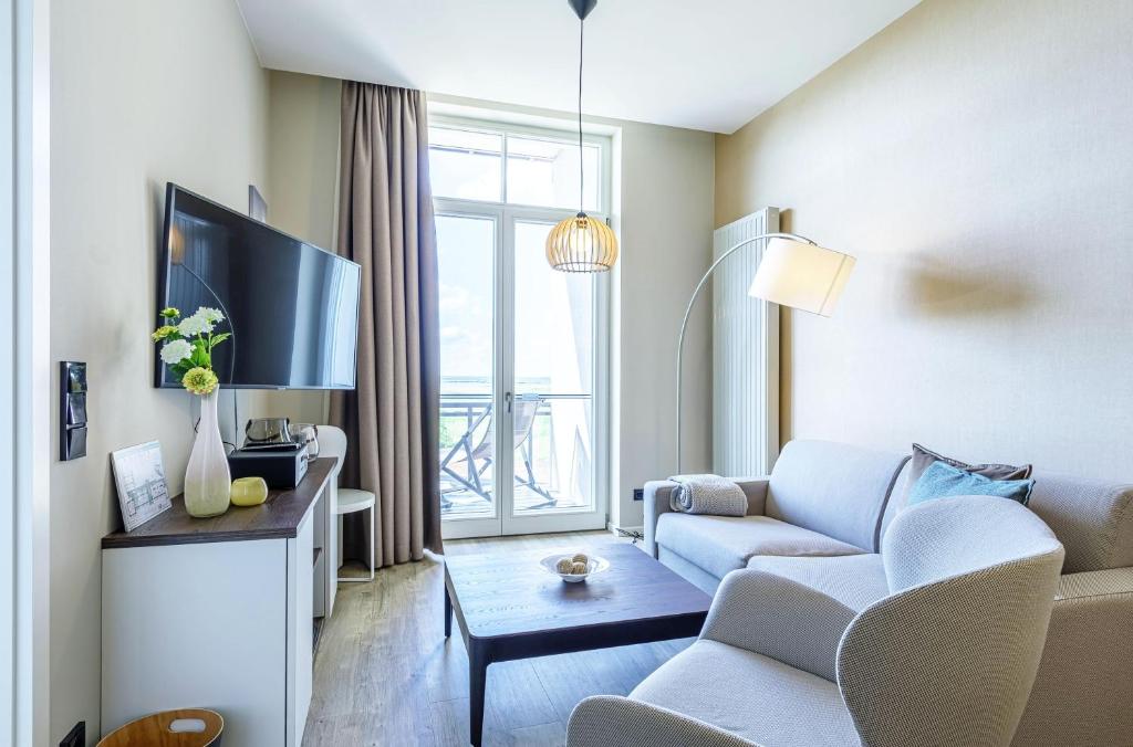 a living room with a couch and a tv at Kleine Welle - Haustierfreundliches Zwei-Zimmer Apartment mit Südbalkon und Platz für drei Personen im ersten Obergeschoss in Wustrow