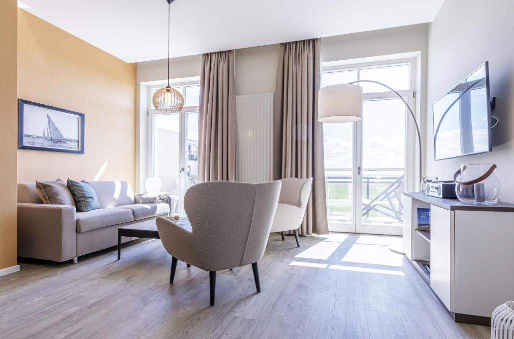 un soggiorno con un divano e una sedia di Ostseefeeling - 5 Sterne Ferienwohnung mit Südbalkon in der Seefahrtschule Wustrow a Wustrow