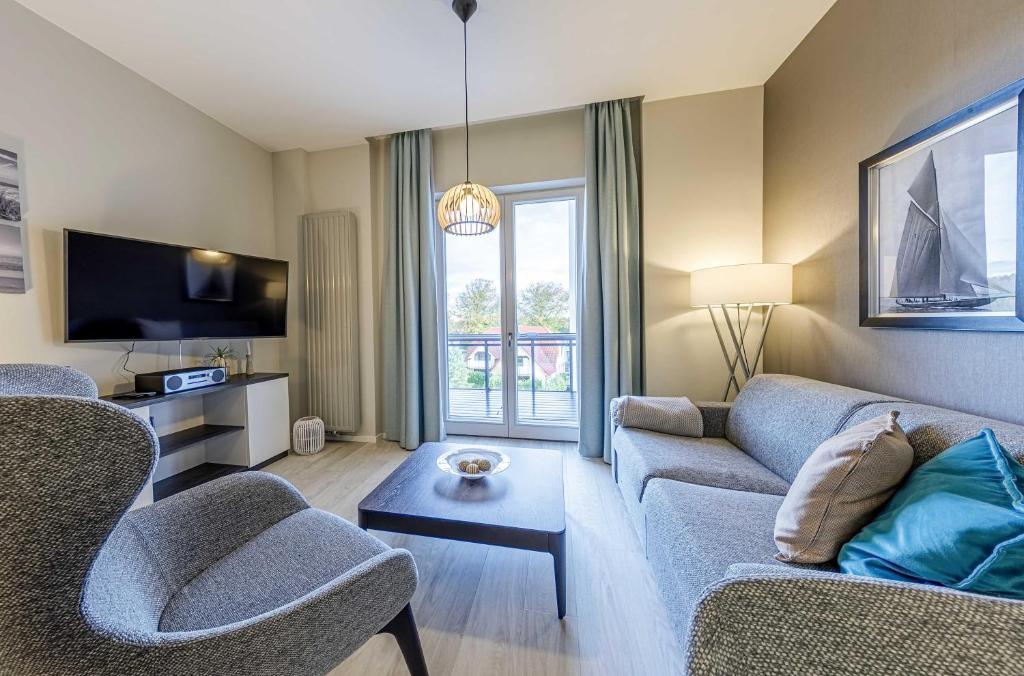 a living room with two couches and a tv at Boddenzeit - Moderne Ferienwohnung mit Nordbalkon, Wellnessbereich und Nähe zum Ostseestrand in Wustrow