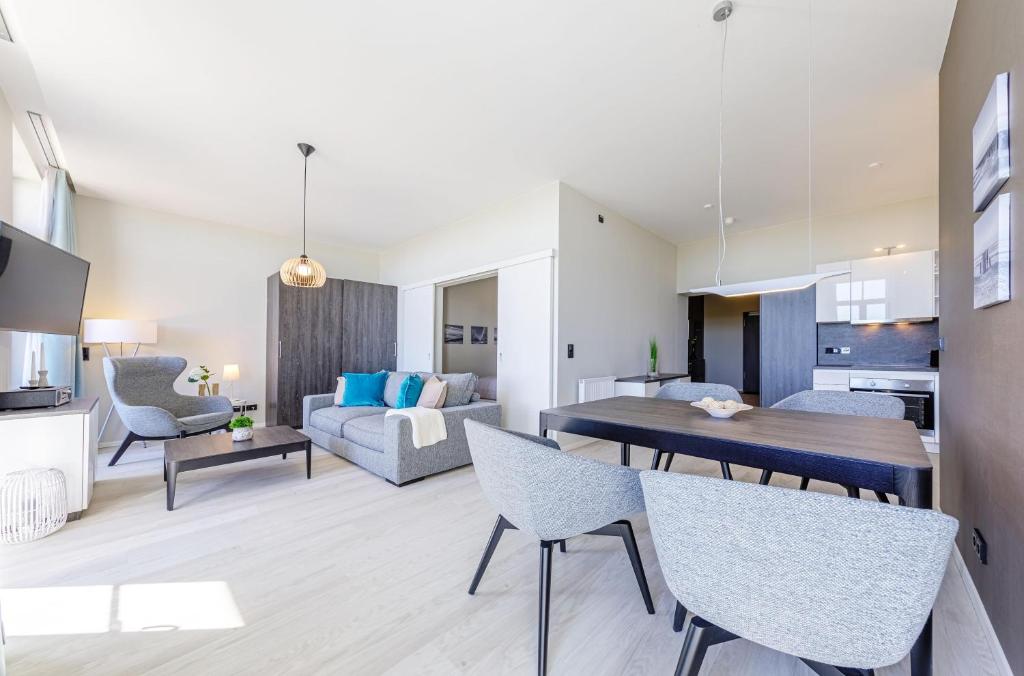 Una sala de estar y un comedor con mesa y sillas. en Große Welle - Moderne 2,5-Zimmer Ferienwohnung mit Südbalkon und Boddenblick, en Wustrow