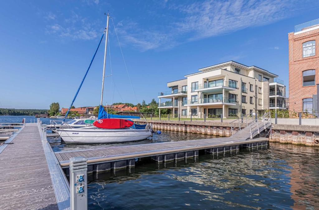 Nordlicht - Modernes Apartment auf Seegrundstück في مالتشو: قارب شراعي راسي على رصيف بجوار مبنى
