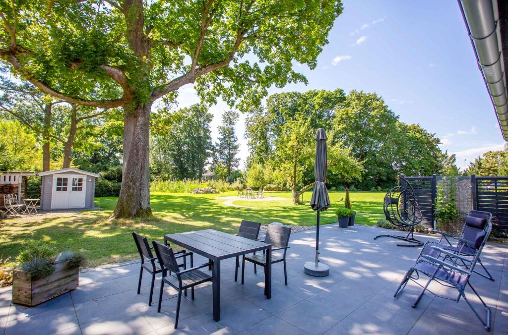 a patio with a table and chairs under a tree at Landidylle in Sembzin in Sembzin