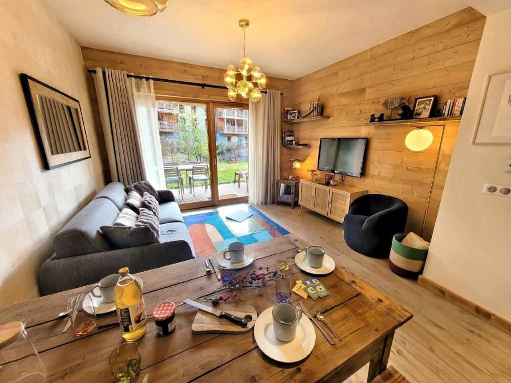 un salon avec un canapé et une table dans l'établissement Appartement neuf avec jardin au cœur des Gets, proche pistes et commerces - FR-1-598-169, aux Gets