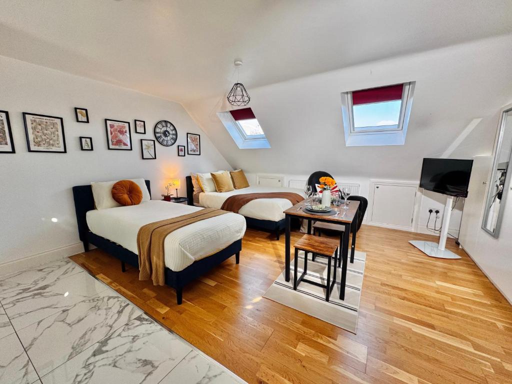 a bedroom with two beds and a table and a television at Ideal Studio Loft 30min to Central London in London