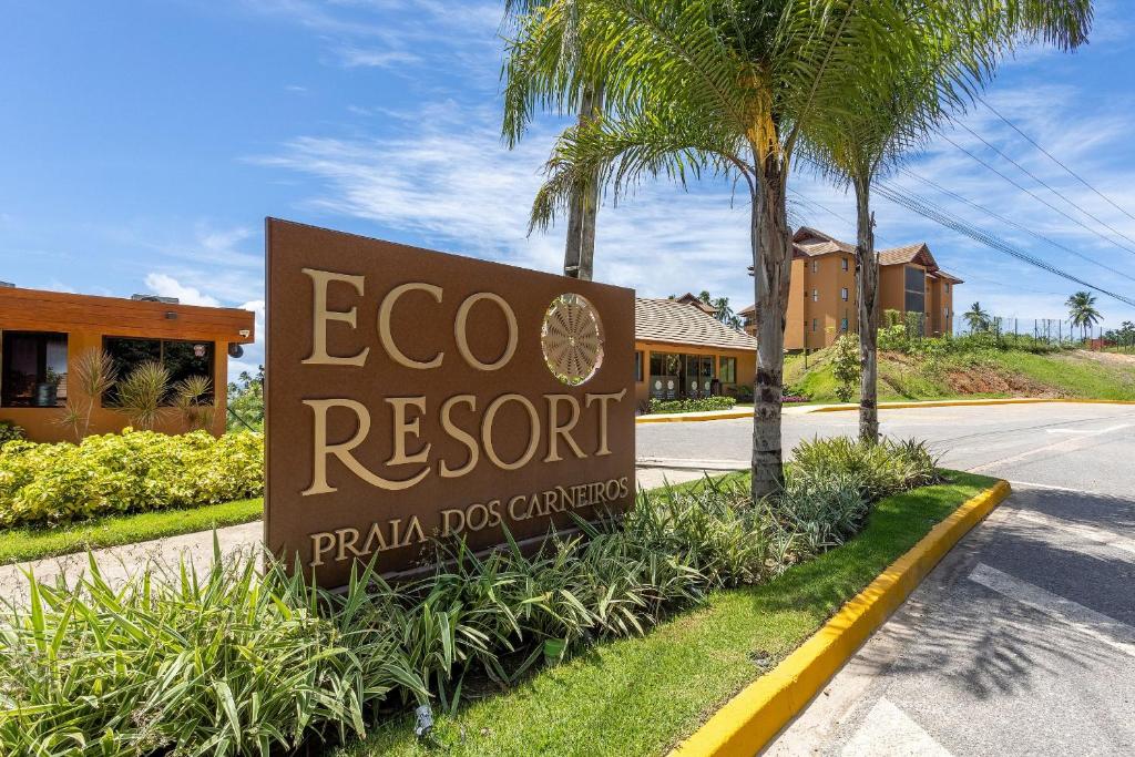a sign for a resort with a palm tree at Flats e apartamentos Eco resort Praia dos Carneiros in Tamandaré