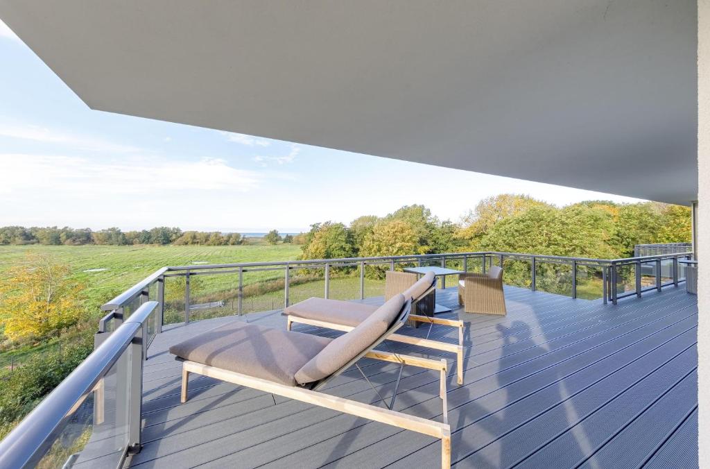 a balcony with a bench and a view of a field at Strandlounge - 5 Sterne-Wohnung mit XXL-Balkon, Wellness & Boddenblick in Wustrow