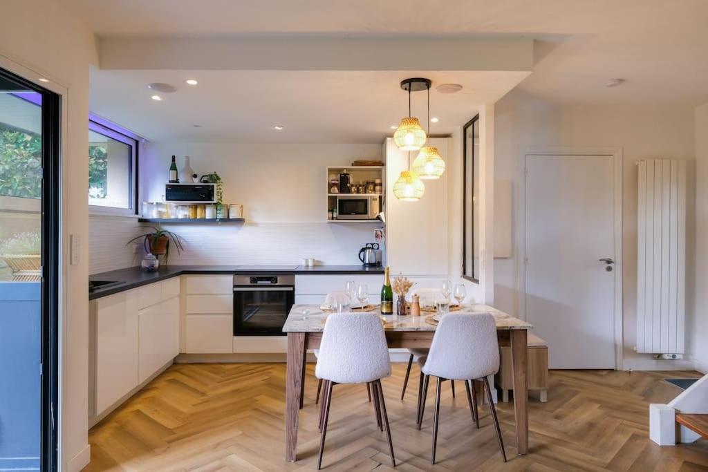 - une cuisine avec une table en bois et des chaises blanches dans l'établissement Maison de charme dans le golf de la baule, à 10 min de la mer, à Saint-André-des-Eaux