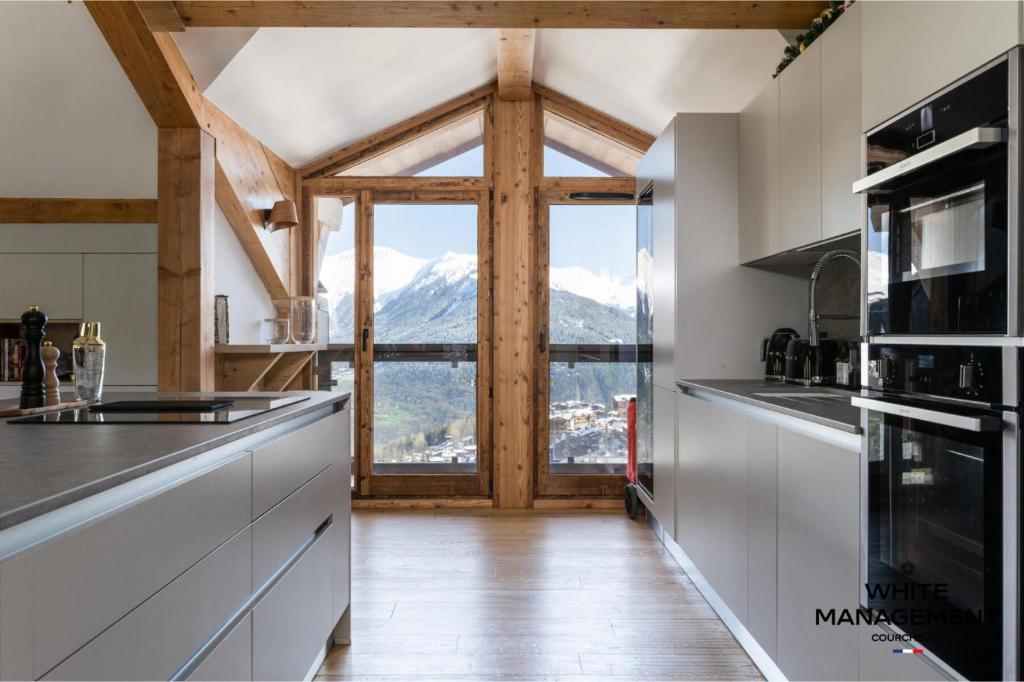 Il comprend une cuisine dotée d'une grande fenêtre offrant une vue sur la montagne. dans l'établissement Résidence Ariondaz Bleuet - Un penthouse au sommet, à Courchevel 1650 MAE-2404, à Courchevel