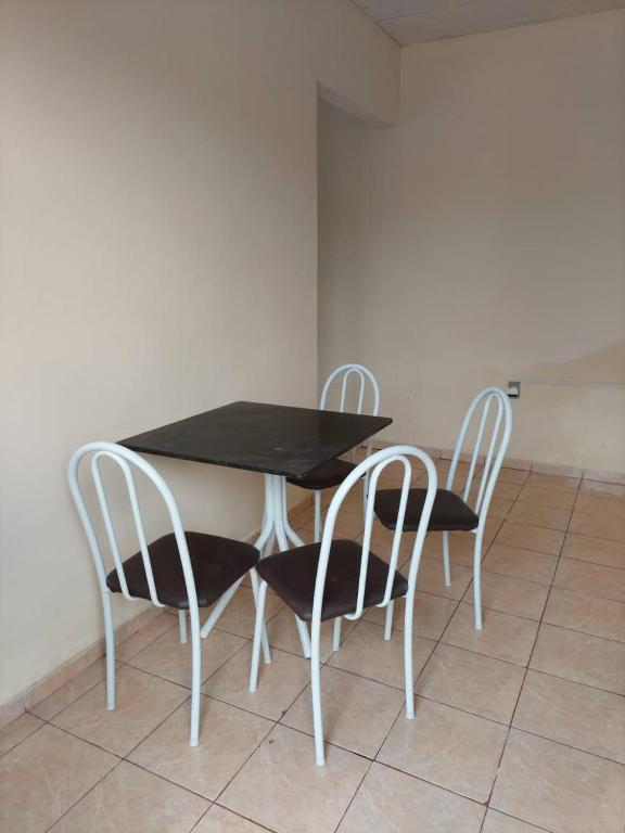 a dining room table with two chairs and a black top at Kitnet bem localizada in Corumbá