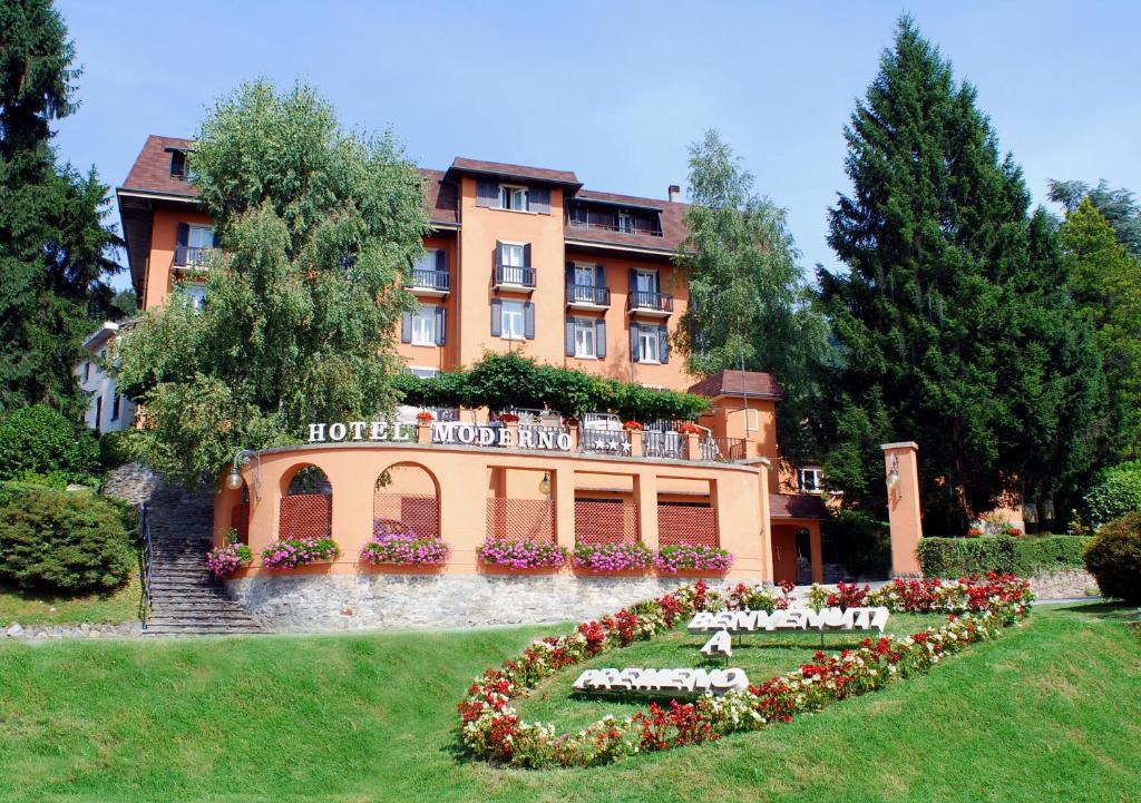 Hotel Moderno في Premeno: فندق يوجد به سرير ازهار امام مبنى