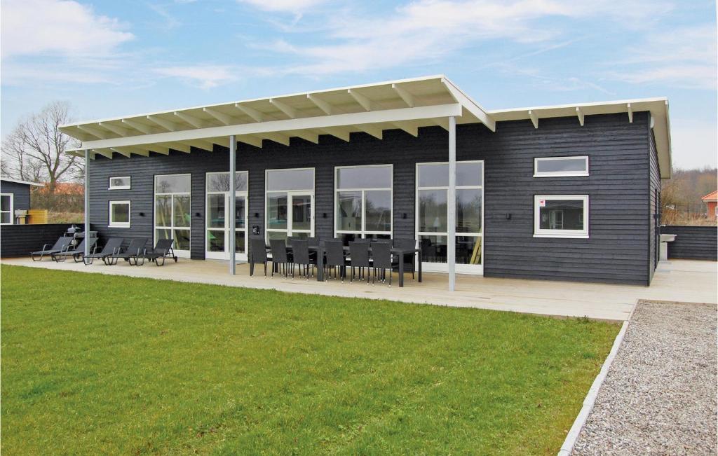 a black house with a roof with tables and chairs at Four-Bedroom Holiday Home Haderslev With A Room Hot Tub 02 in Knud
