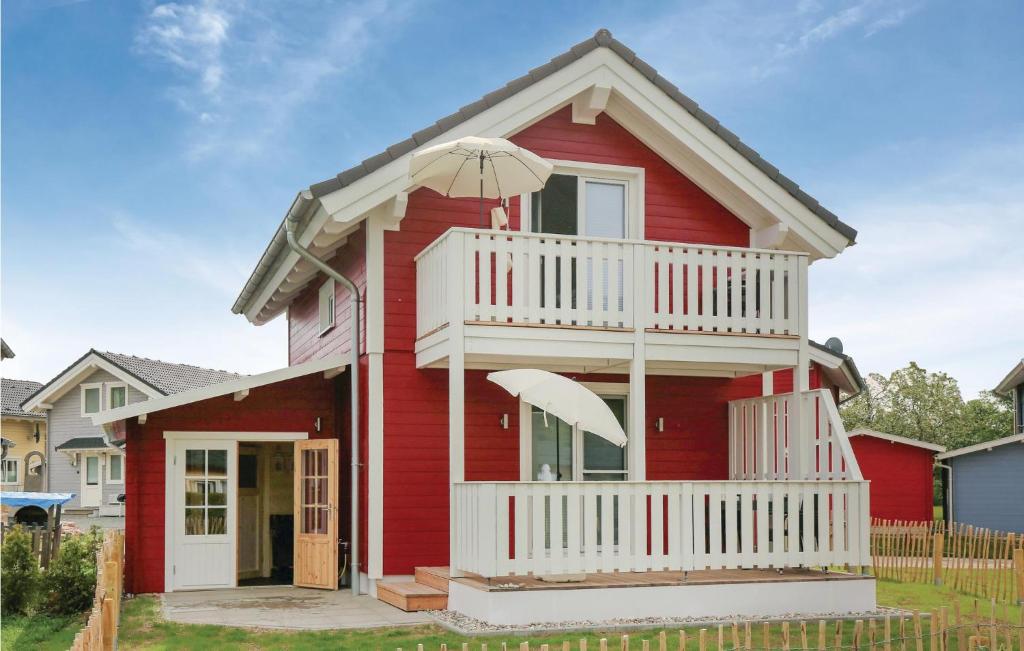 ein rotes Haus mit einem weißen Balkon und einem Regenschirm in der Unterkunft Seehund in Süssau