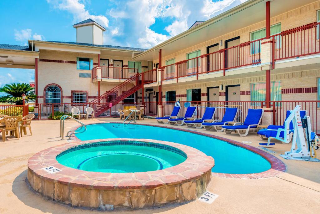 a pool in front of a hotel with blue chairs at Hill Country Inn & Suites - New Braunfels, Gruene in New Braunfels