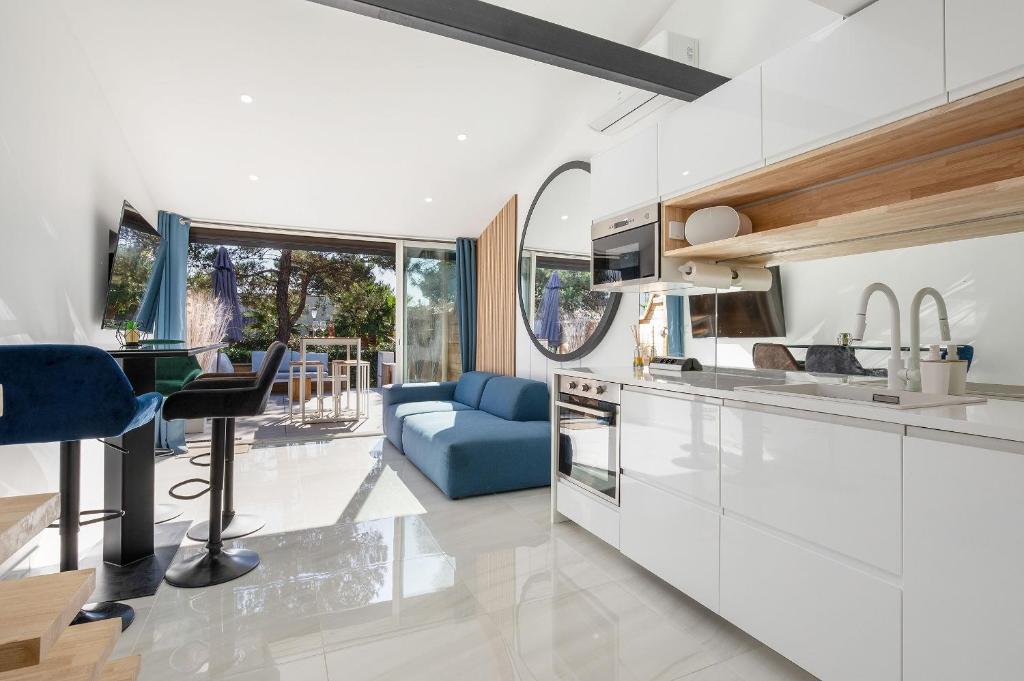 une cuisine avec des placards blancs et un canapé bleu dans l'établissement Village Naturiste R4N - La Villa GreenWood, au Cap d'Agde