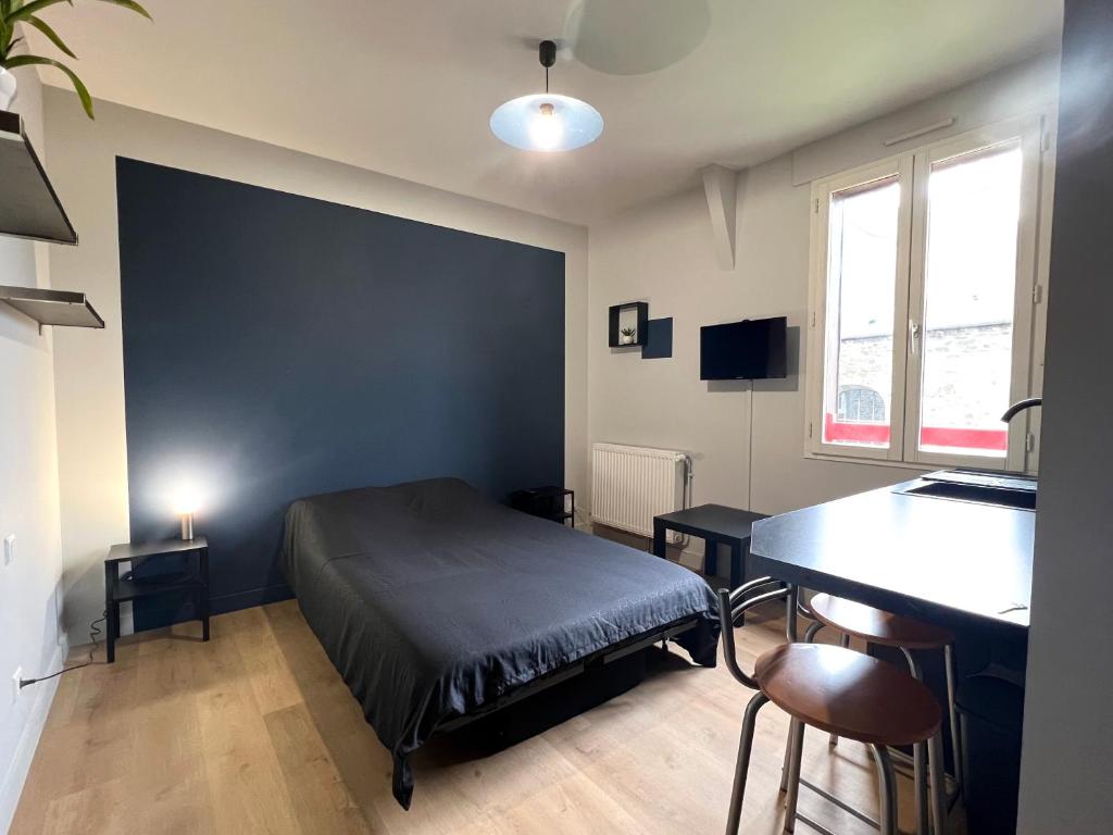 a bedroom with a bed and a desk and a table at Résidence des Carmes in Dol-de-Bretagne