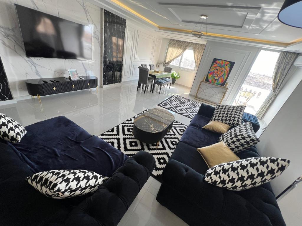 a living room with a blue couch and a tv at Pyramids Panorama Suites in ‘Ezbet `Abd el-Ḥamîd