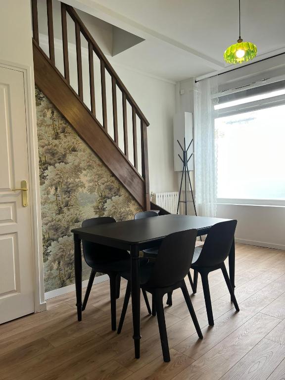 une salle à manger avec une table et des chaises noires dans l'établissement Appartement en duplex - M4 et RER B Arcueil-Cachan, à Bagneux