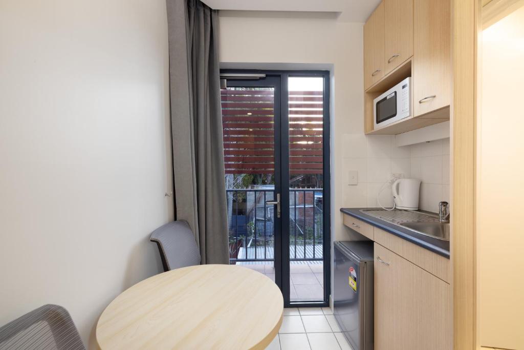 a small kitchen with a table and a balcony at Asraport Motel in Brisbane