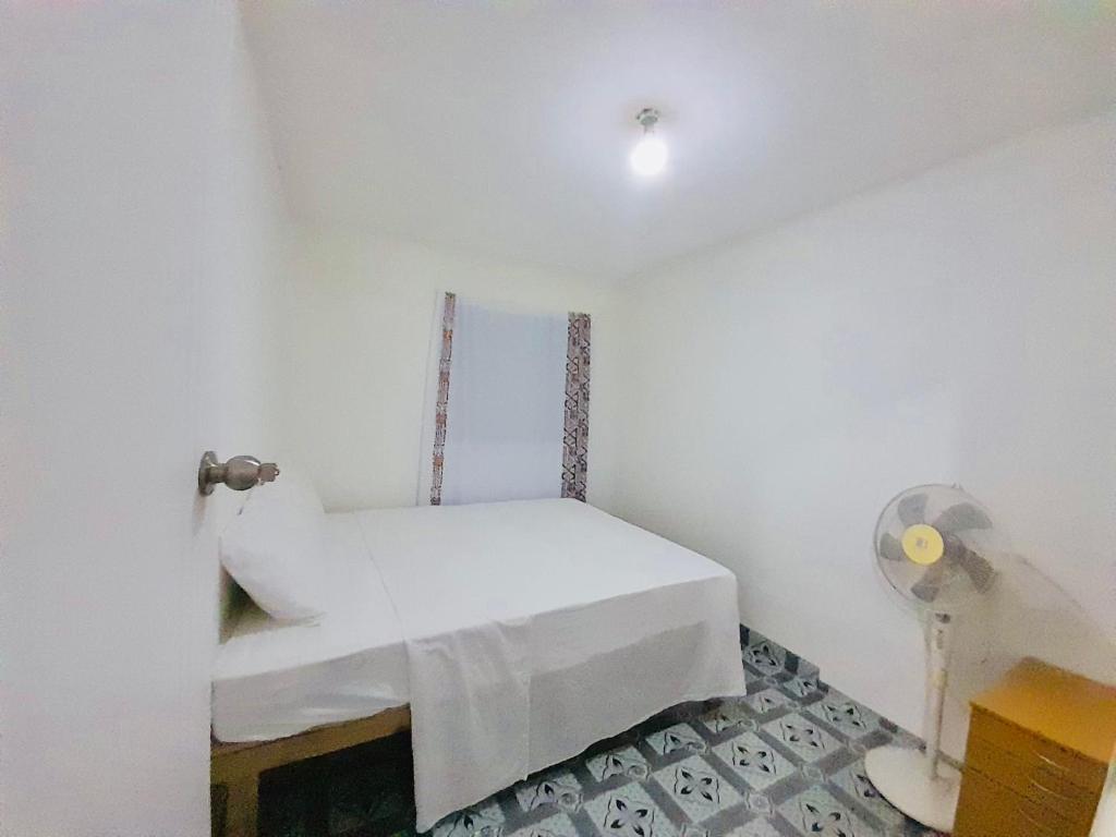 ein Zimmer mit einem weißen Bett mit einem Ventilator in der Unterkunft Private Twin Room - Horizon Tonga Cottage in Nuku‘alofa