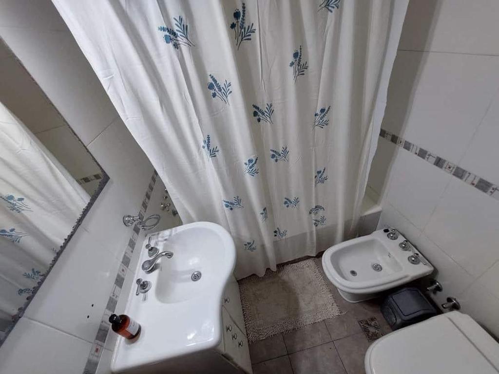 a bathroom with a sink and a toilet and a shower curtain at Casa alquiler temporario miramar in Miramar