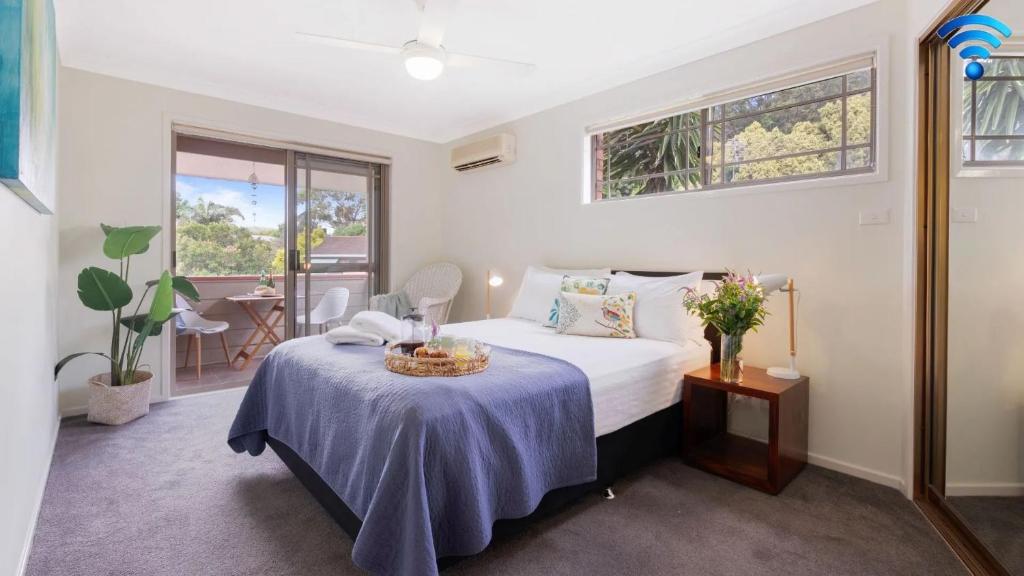 a bedroom with a bed with a table and a window at Bombo Blue in Kiama